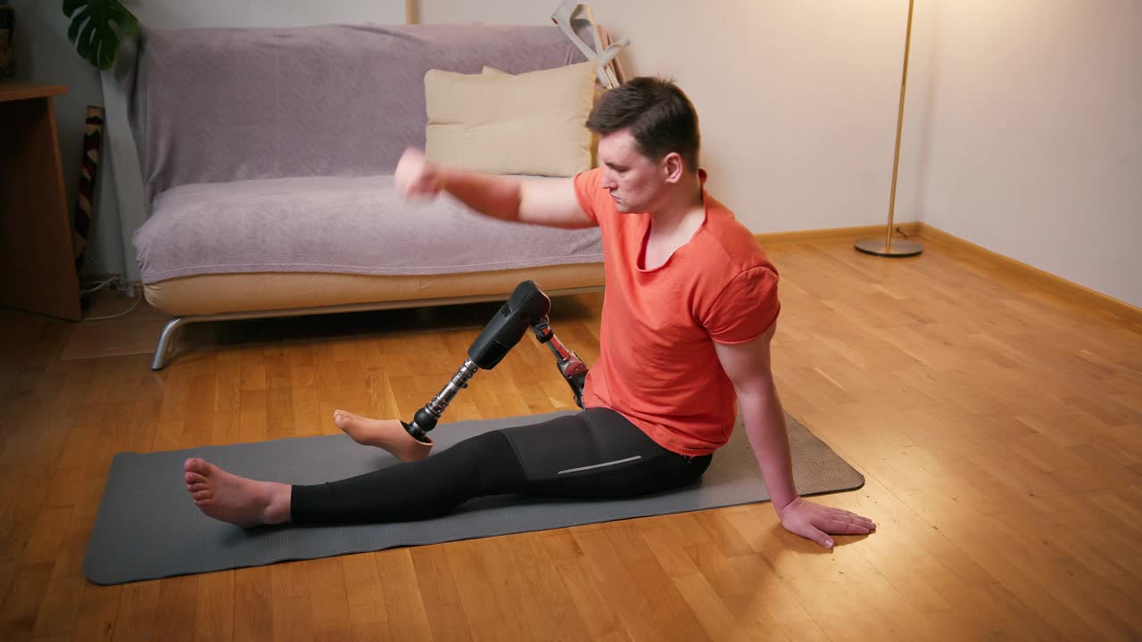 男性义肢残疾截肢者，利用经股义肢人工装置在家进行伸展康复体育锻炼。截肢残疾人的日常生活视频素材