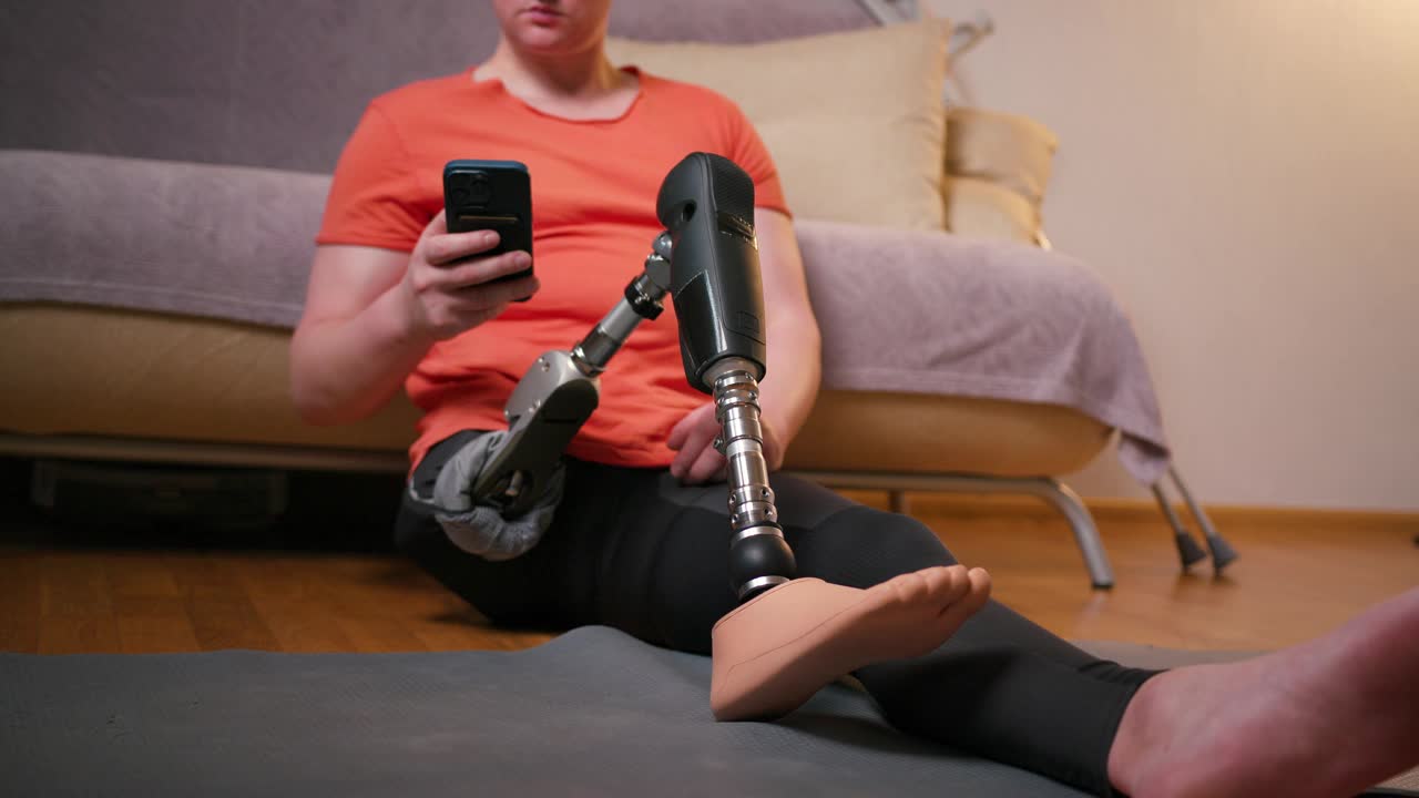 一名膝部以上假腿残疾的截肢者在家中使用智能手机安装经股腿假体人工装置。截肢残障人士的日常生活视频素材