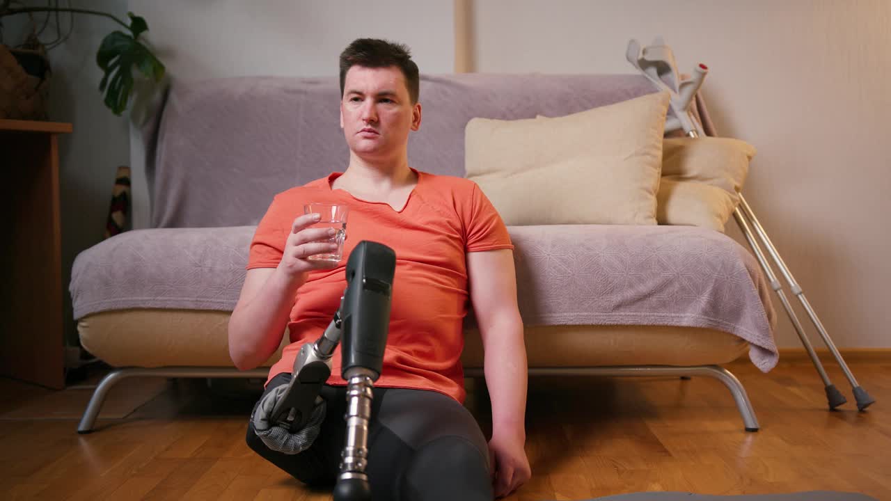 一名膝部以上假腿残疾的截肢者在家中饮水。截肢残障人士的日常生活视频素材