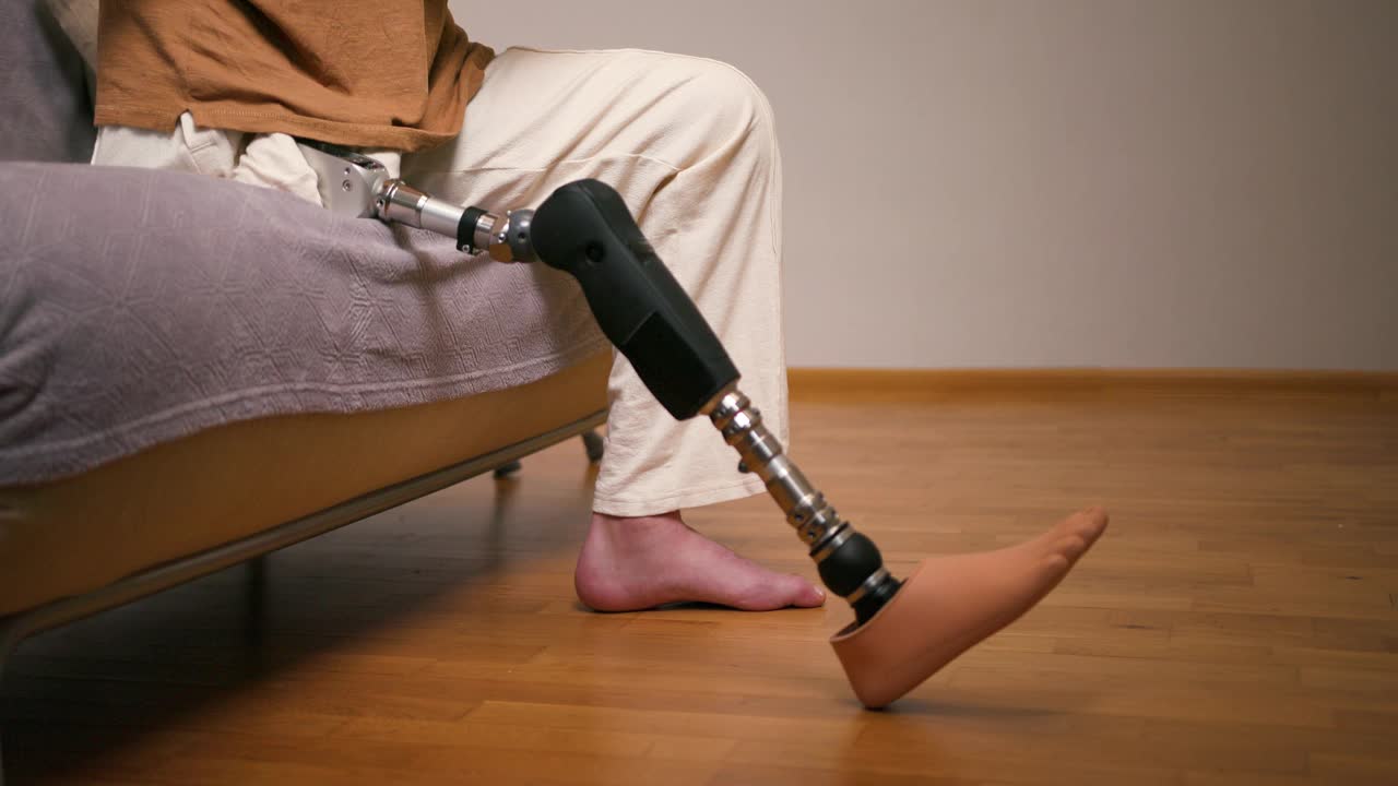 男截肢者膝以上经股腿假体人工装置在家中的近照。截肢残障人士的日常生活视频素材