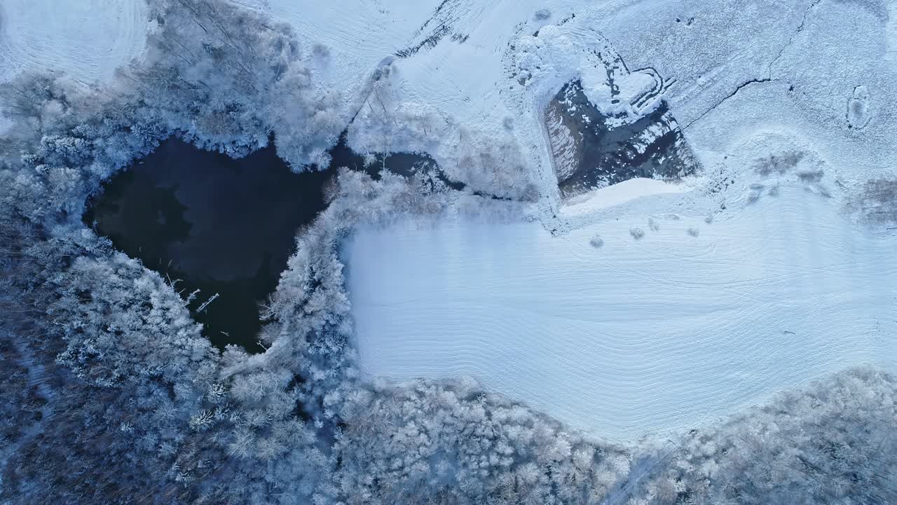 冬天，池塘被白雪覆盖的土地包围。-航拍视频素材