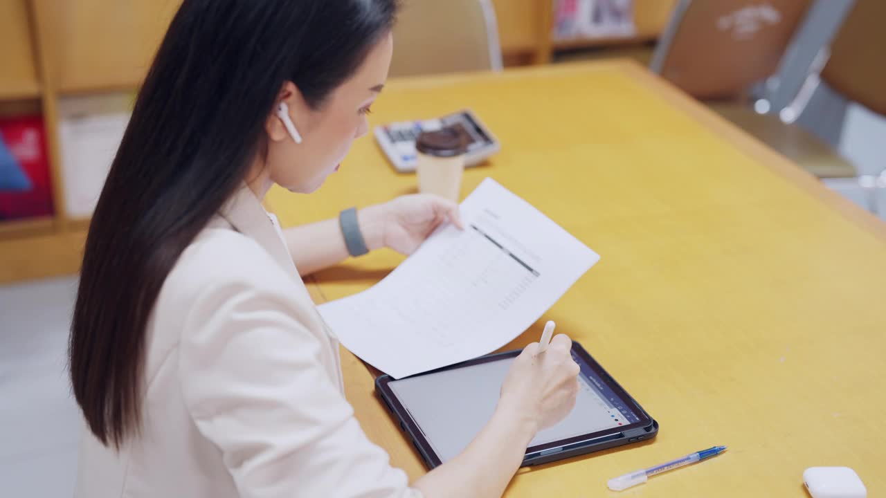 一个女人坐在桌子旁，手里拿着一块写字板和一支笔视频素材