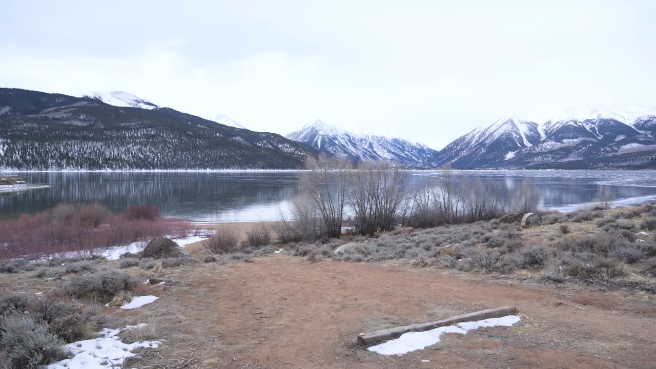 一对情侣走向冰封的湖泊，背景是雪山，静悄悄的视频素材