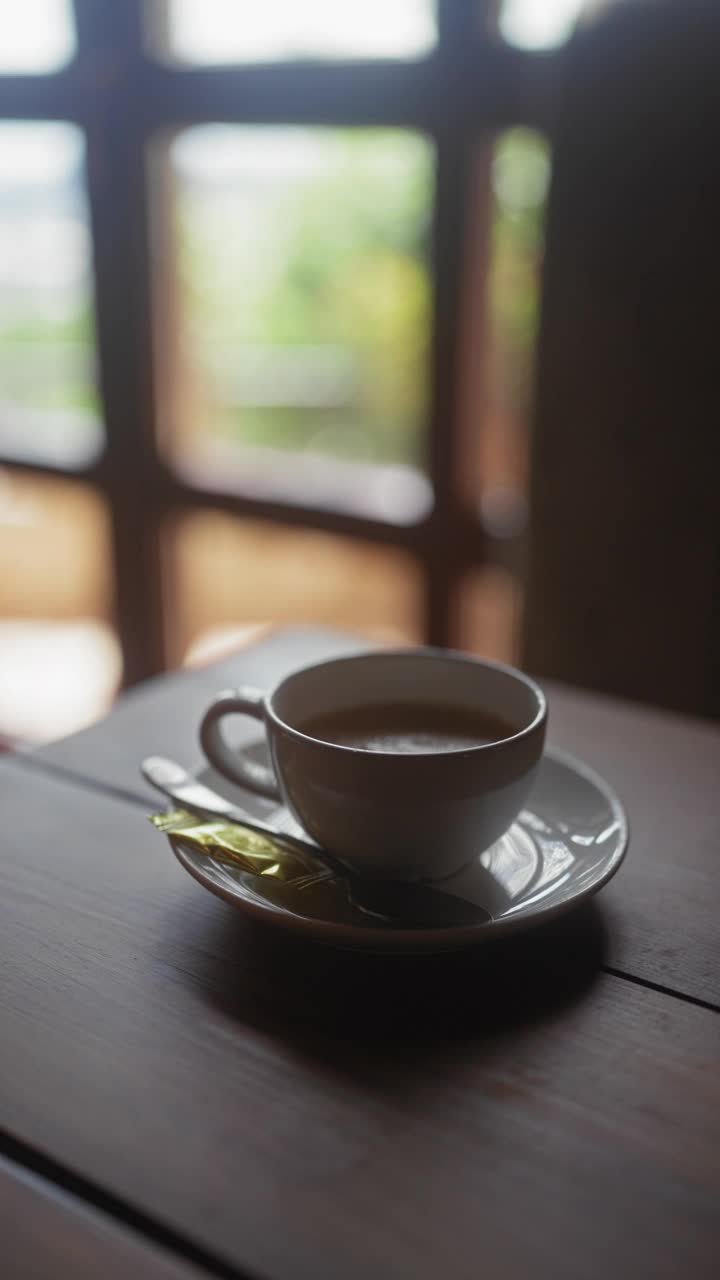 一个人在一张自然背景模糊的木桌上搅拌一杯茶视频素材