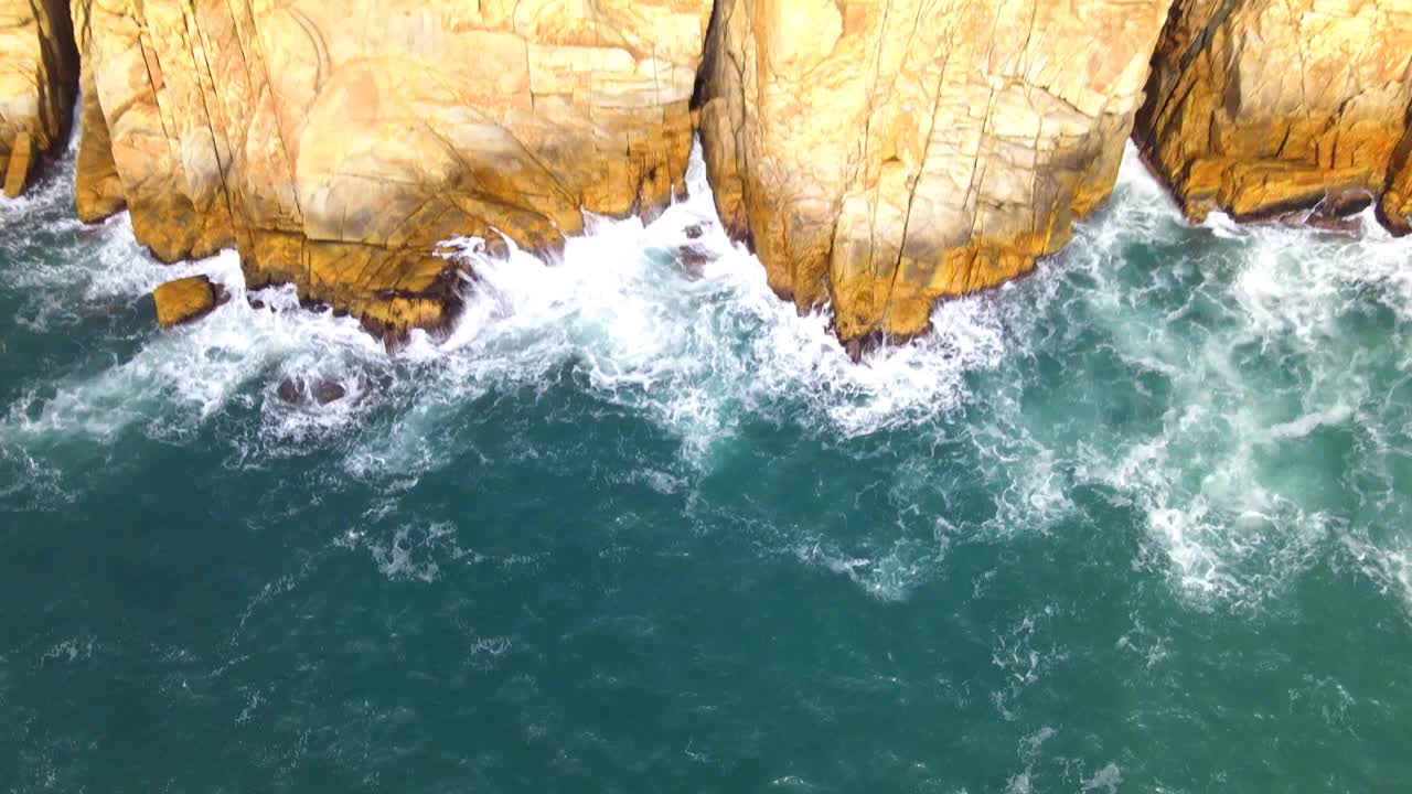 在香港一个阳光明媚的夏日，鸟瞰海浪冲击岩石海滩视频素材