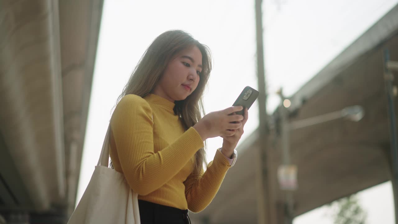 一名妇女在等出租车时使用手机。视频素材