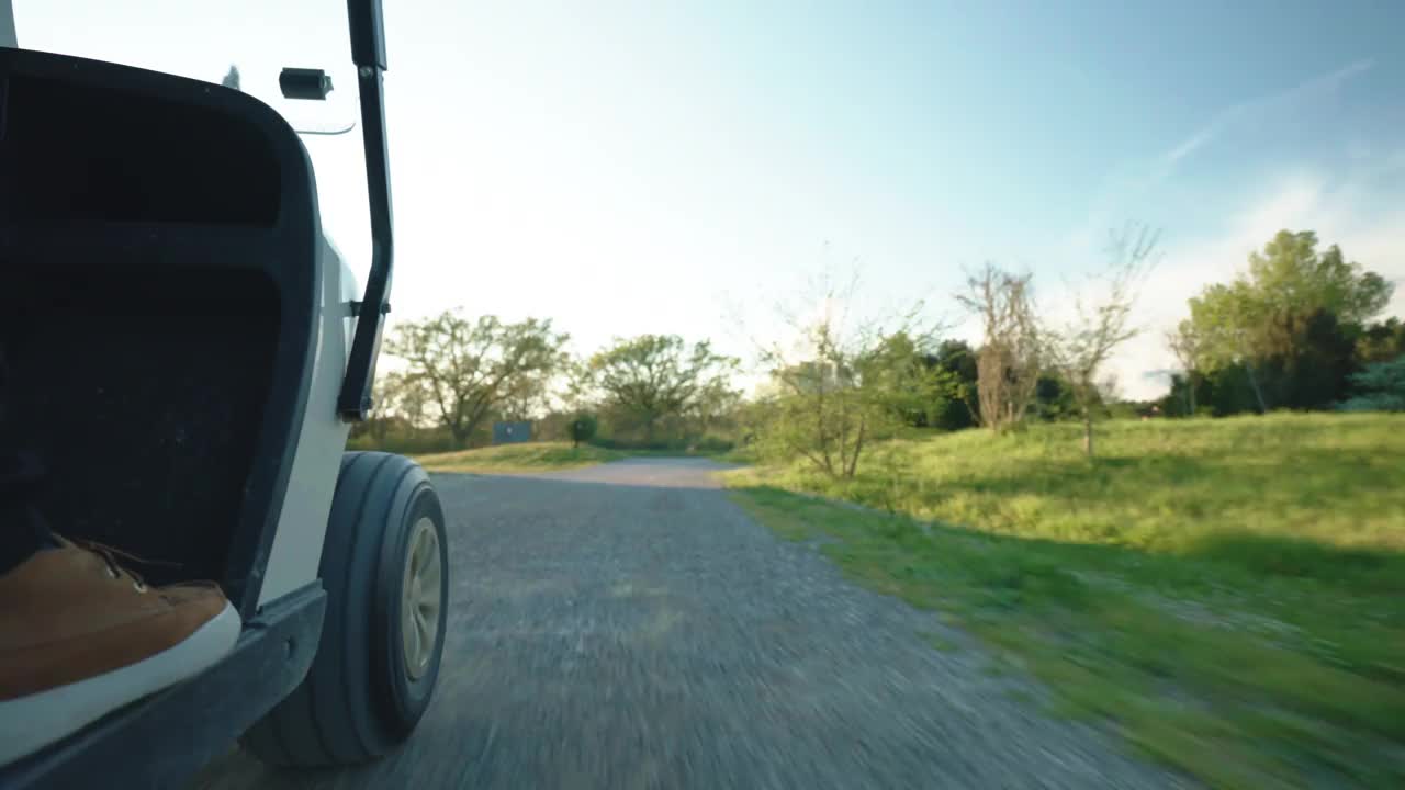 高尔夫俱乐部的球员驾驶着运动高尔夫球车沿着道路穿过令人惊叹的绿色修剪草坪，运动游戏爱好者和休闲的概念视频下载