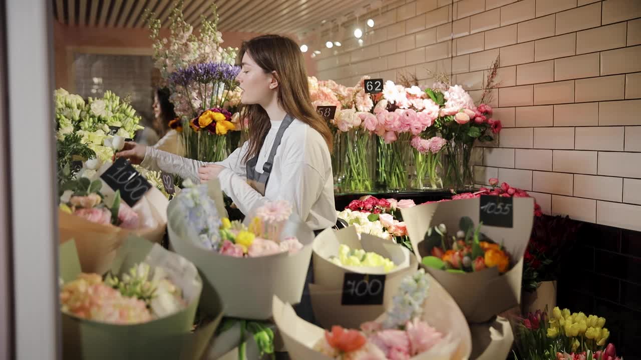 花匠从花店的冰箱里挑选花束。年轻的女零售商在花店准备订货。鲜花冰箱视频素材