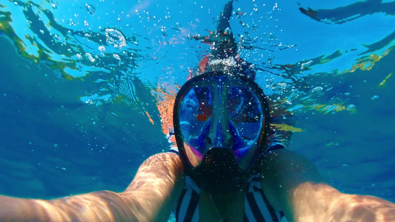 一个女人在一个阳光明媚的夏日里浮潜。水下视图视频素材