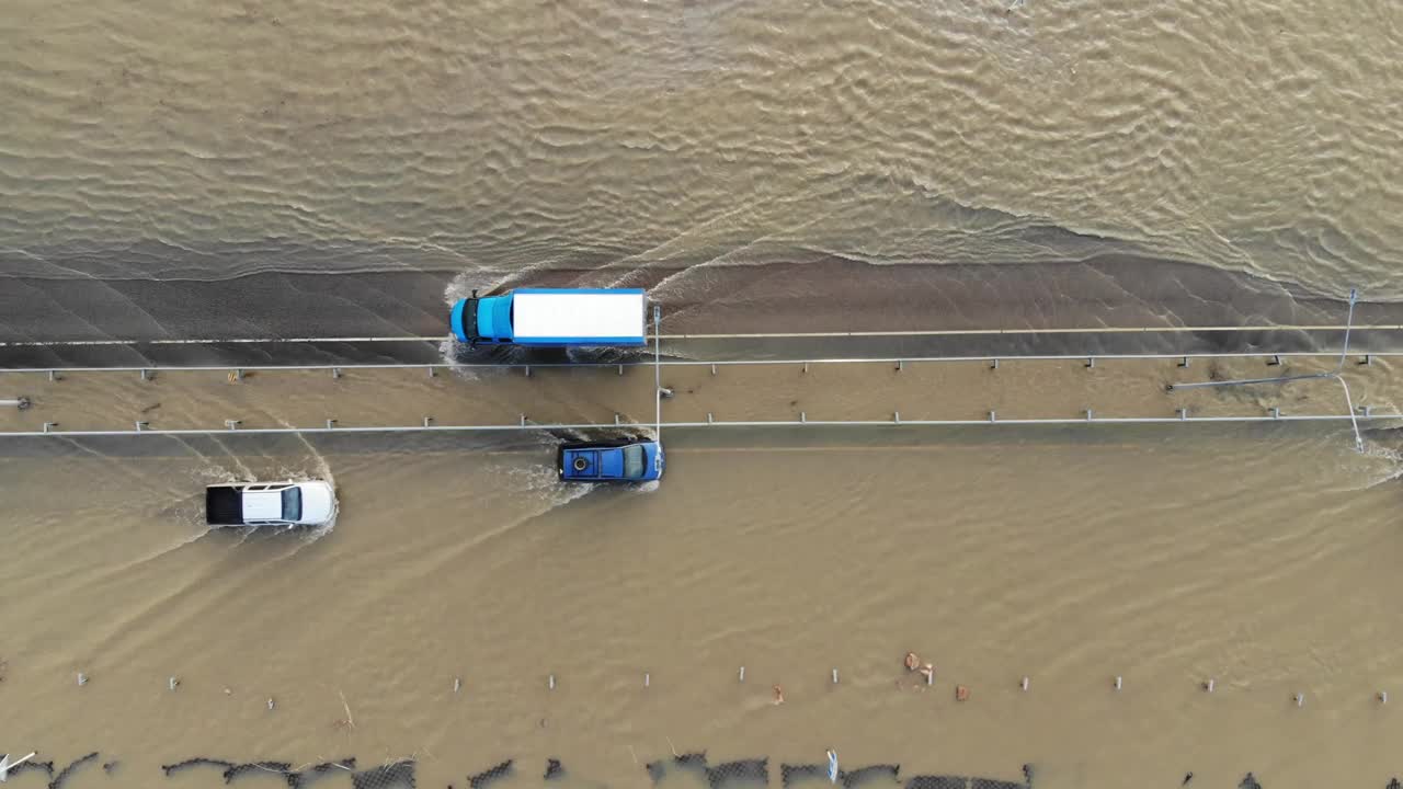 汽车和卡车行驶在被洪水淹没的高速公路上，在雨雪融化后的洪水中行驶视频下载