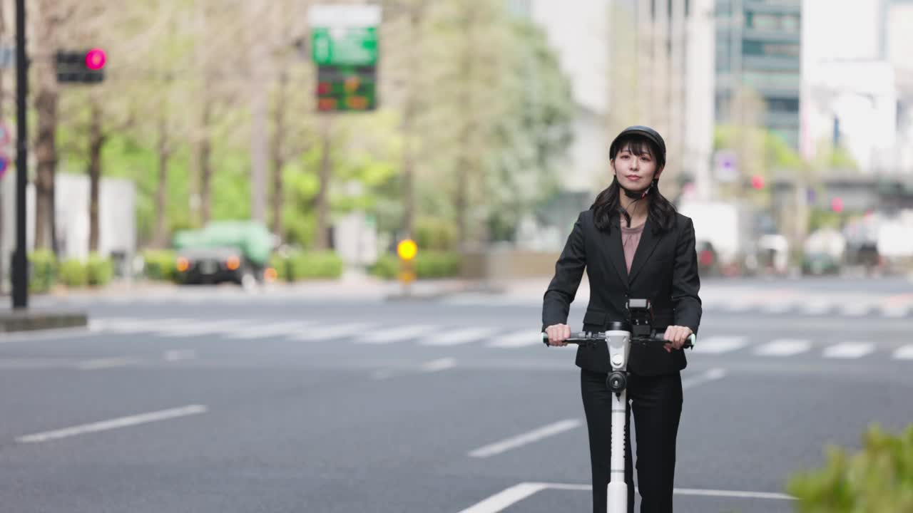 年轻的女商人在城市街道上骑着电动摩托车视频素材