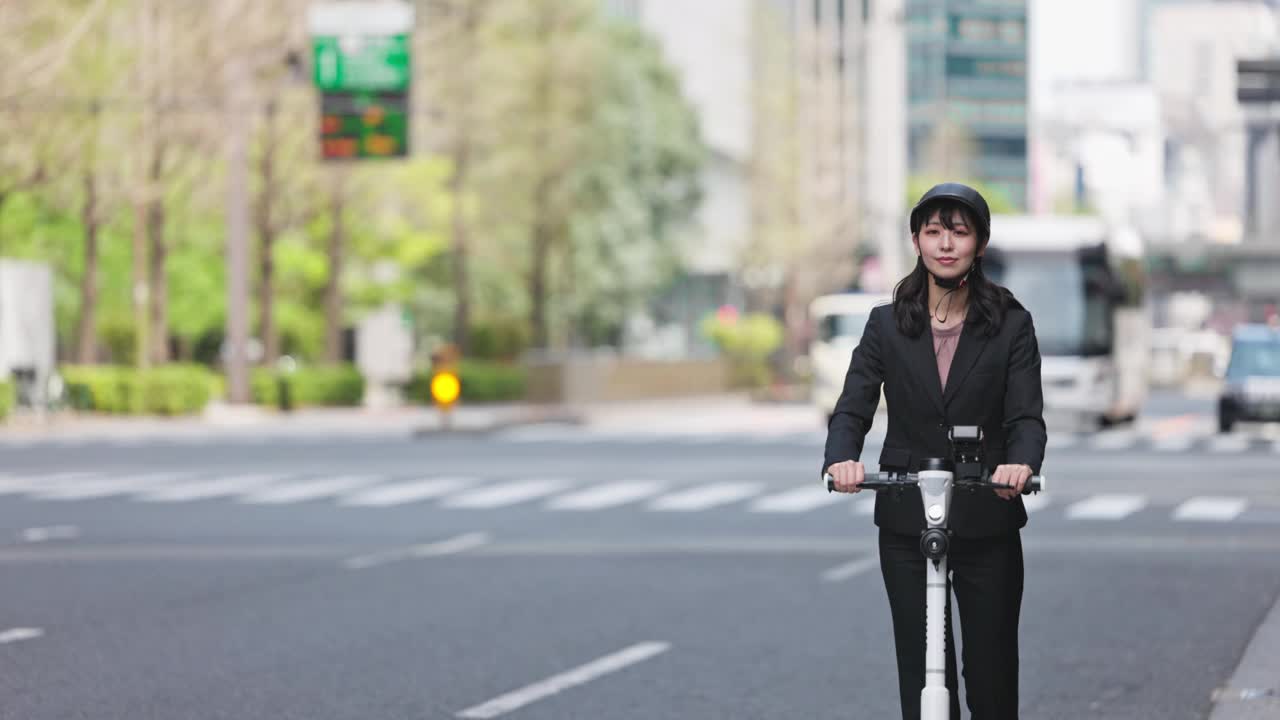 年轻的女商人在城市街道上骑着电动摩托车视频素材