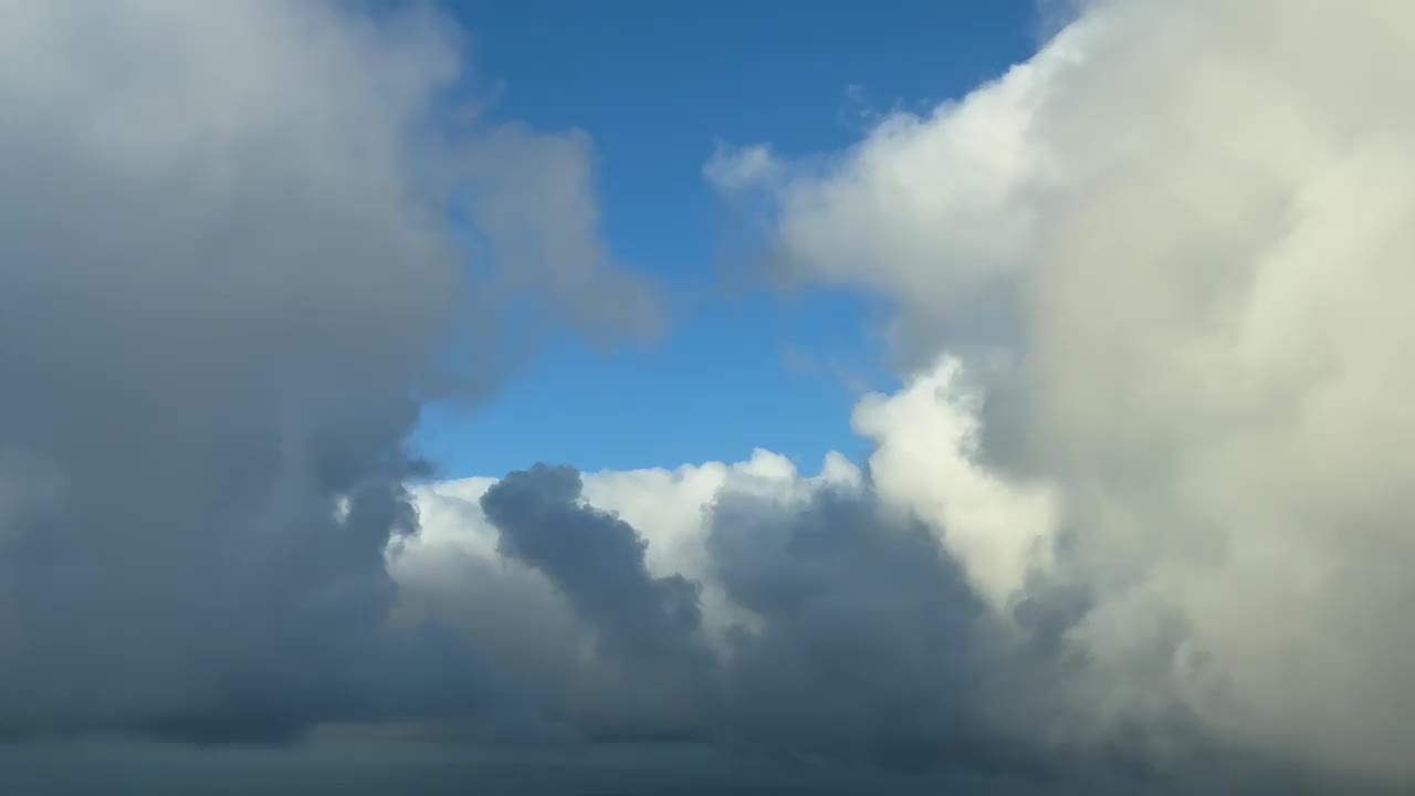 飞行员POV飞过蓝天，上面有一些蓬松的积云。沉浸式独特视角。从飞机机舱里的飞行员看到的视频素材