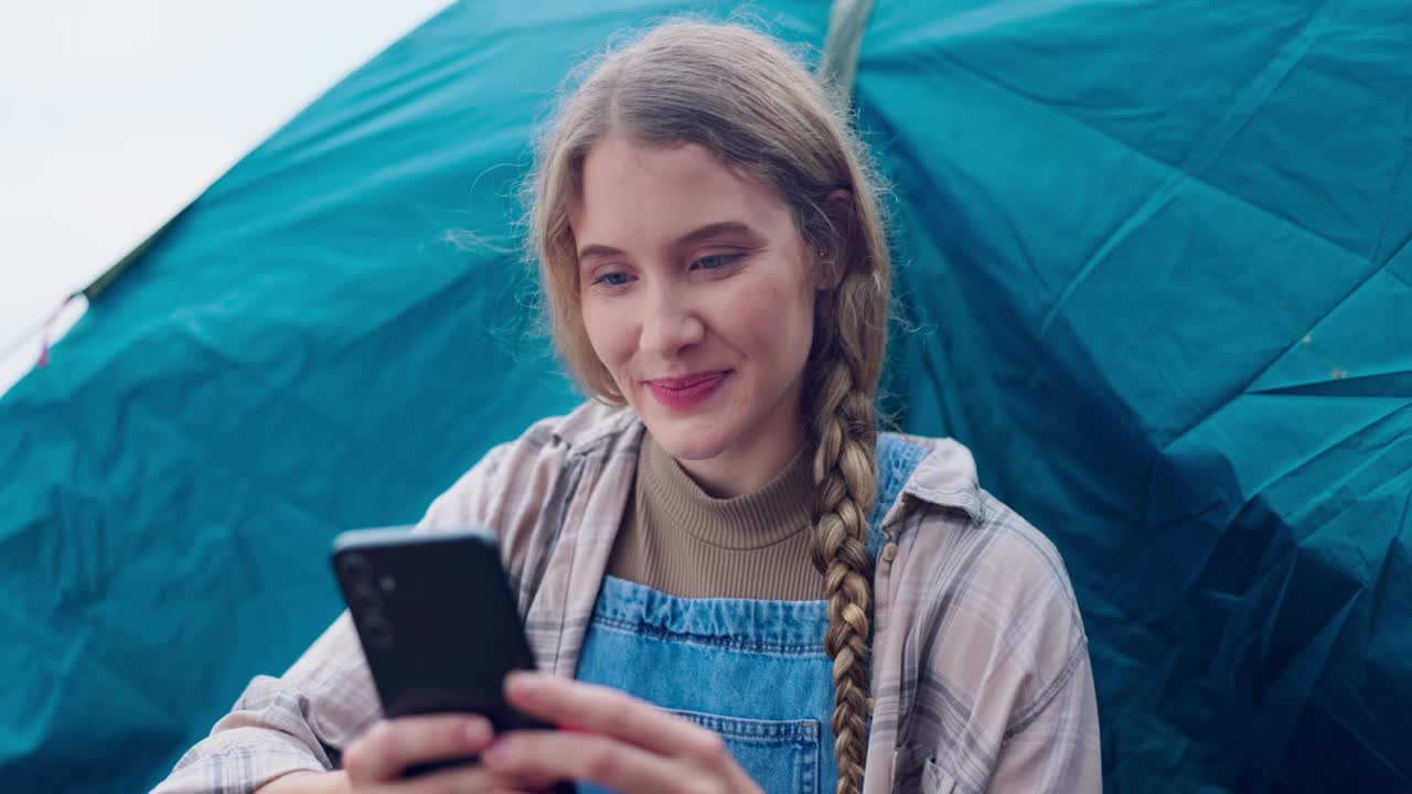 露营，快乐和女人在帐篷与电话在冒险，假期和户外度假。在瑞典，大自然、放松和人在露营地用智能手机进行社交媒体、在线帖子和旅行更新视频素材