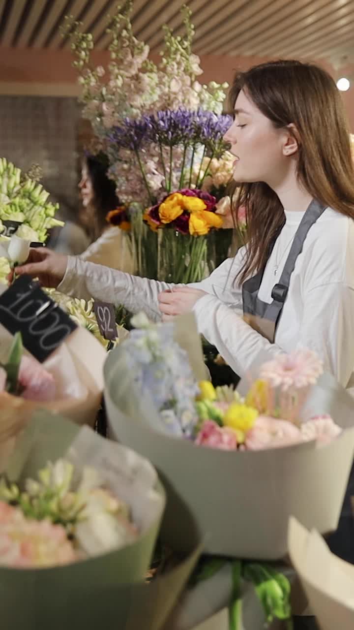 在花店的冰箱里，花匠在为花束挑选鲜花。年轻的女零售商在花店准备订货。鲜花冰箱视频素材