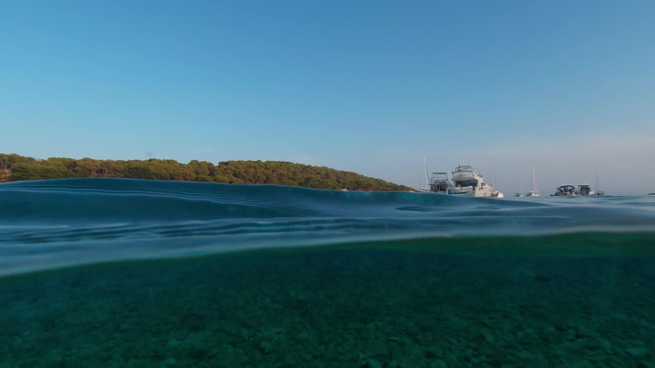 在一个阳光明媚的夏日，海湾里停泊着风景如画的游艇。上面和下面。视频素材