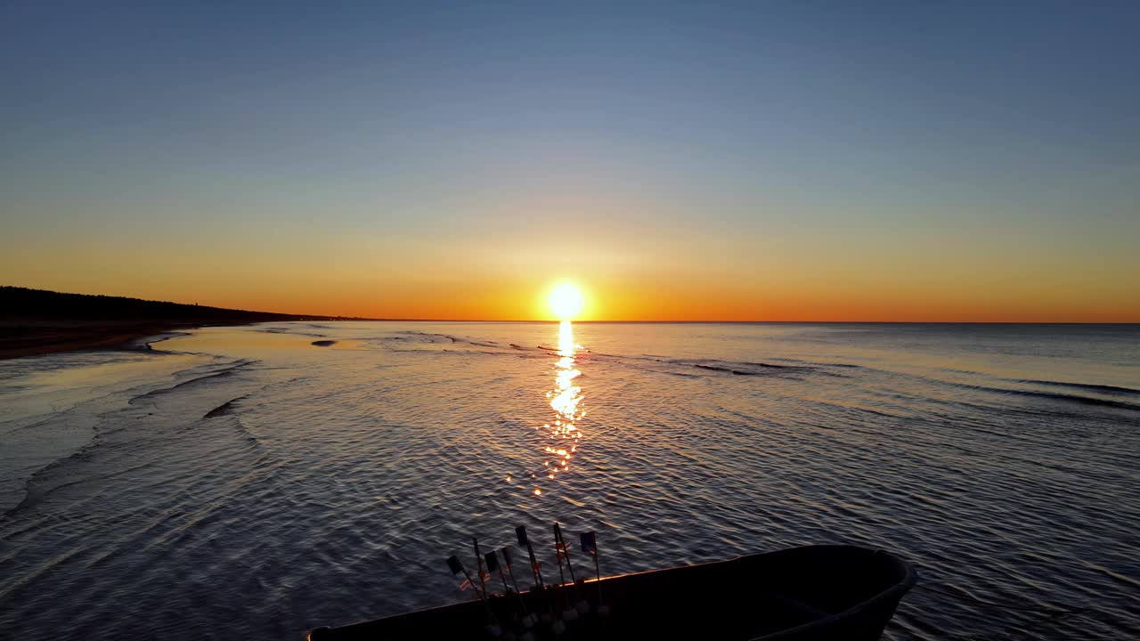 日落时，一艘渔船漂浮在海上。天空是一个美丽的混合橙色和粉红色的色调，波罗的海海岸线视频素材