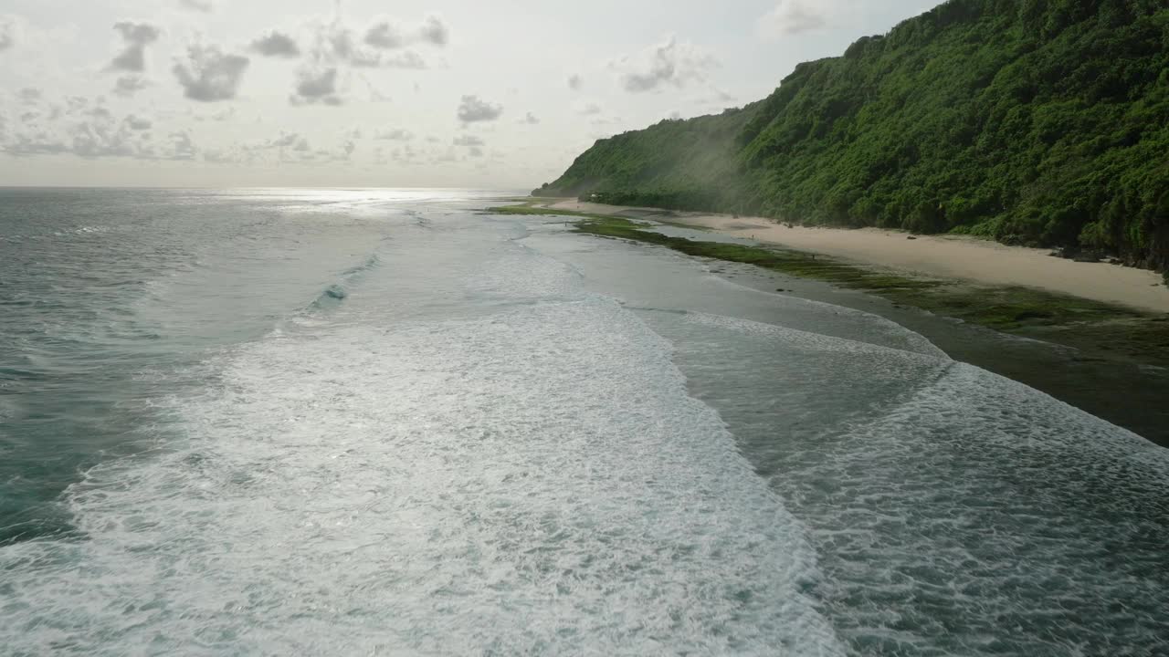 蓝色的海浪冲击着巴厘岛的沙滩和丛林视频素材