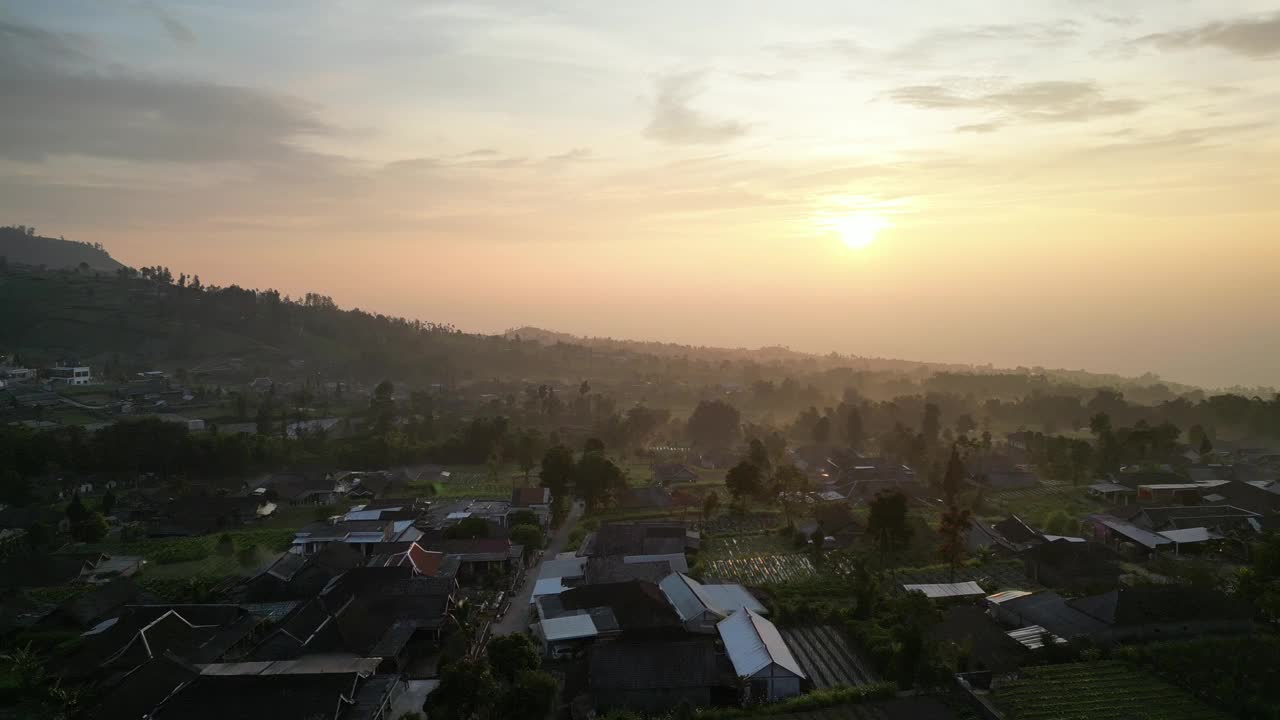 鸟瞰美丽的日出在Merbabu山的山腰在早上与蔬菜花园和村庄定居点或住房在Selo Boyolali，中爪哇，印度尼西亚-直运动。视频素材