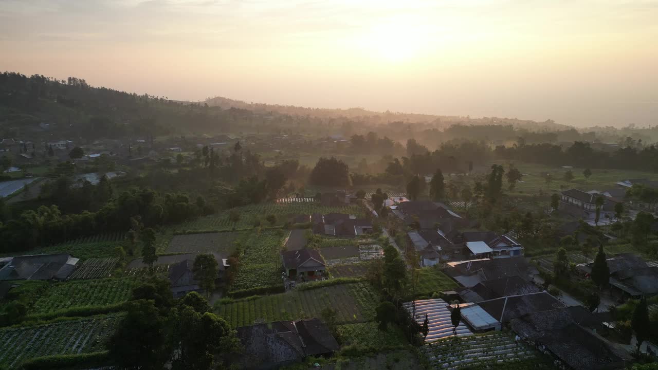 鸟瞰美丽的日出在Merbabu山的山腰在早上与蔬菜花园和村庄定居点或住房在Selo Boyolali，中爪哇，印度尼西亚-直运动。视频素材