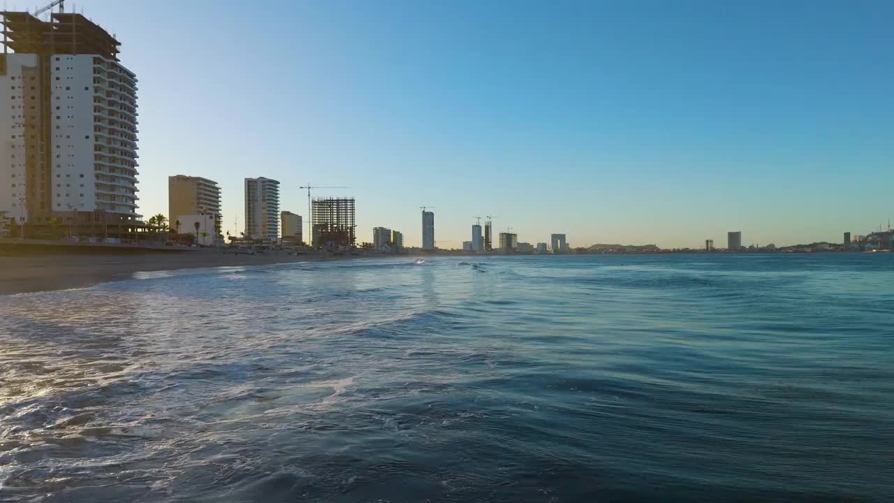 马萨特兰的黎明时分，无人机在海岸线上空滑翔。在一股温柔的海浪上，两只鹈鹕向观众飞去，优雅地从镜头下经过，捕捉到海岸美景的惊人时刻。视频素材