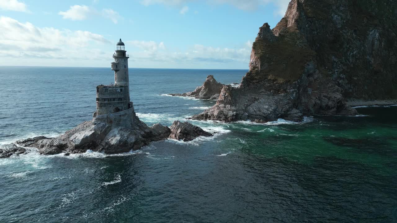 海中的岩石海角景观和灯塔的俯视图。夹。岛上岩石岬角的美丽风景和废弃的灯塔。海景与岩石海角和灯塔在阳光明媚的日子视频素材