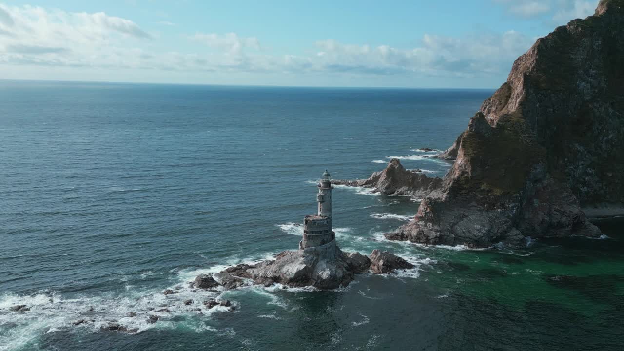 海中的岩石海角景观和灯塔的俯视图。夹。岛上岩石岬角的美丽风景和废弃的灯塔。海景与岩石海角和灯塔在阳光明媚的日子视频素材