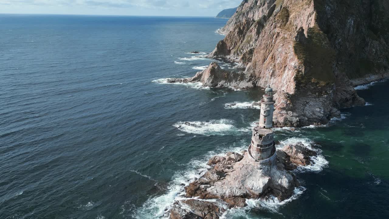 海中的岩石海角景观和灯塔的俯视图。夹。岛上岩石岬角的美丽风景和废弃的灯塔。海景与岩石海角和灯塔在阳光明媚的日子视频素材