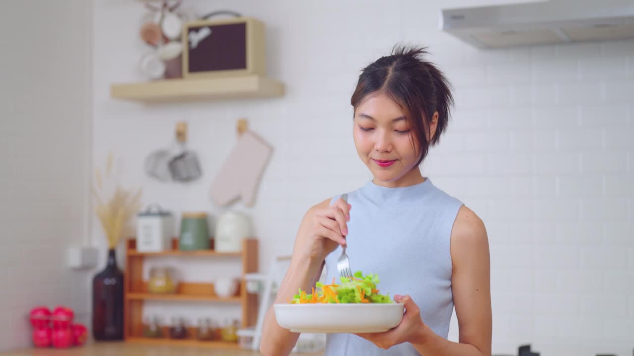 年轻女子在厨房享用新鲜沙拉。视频素材