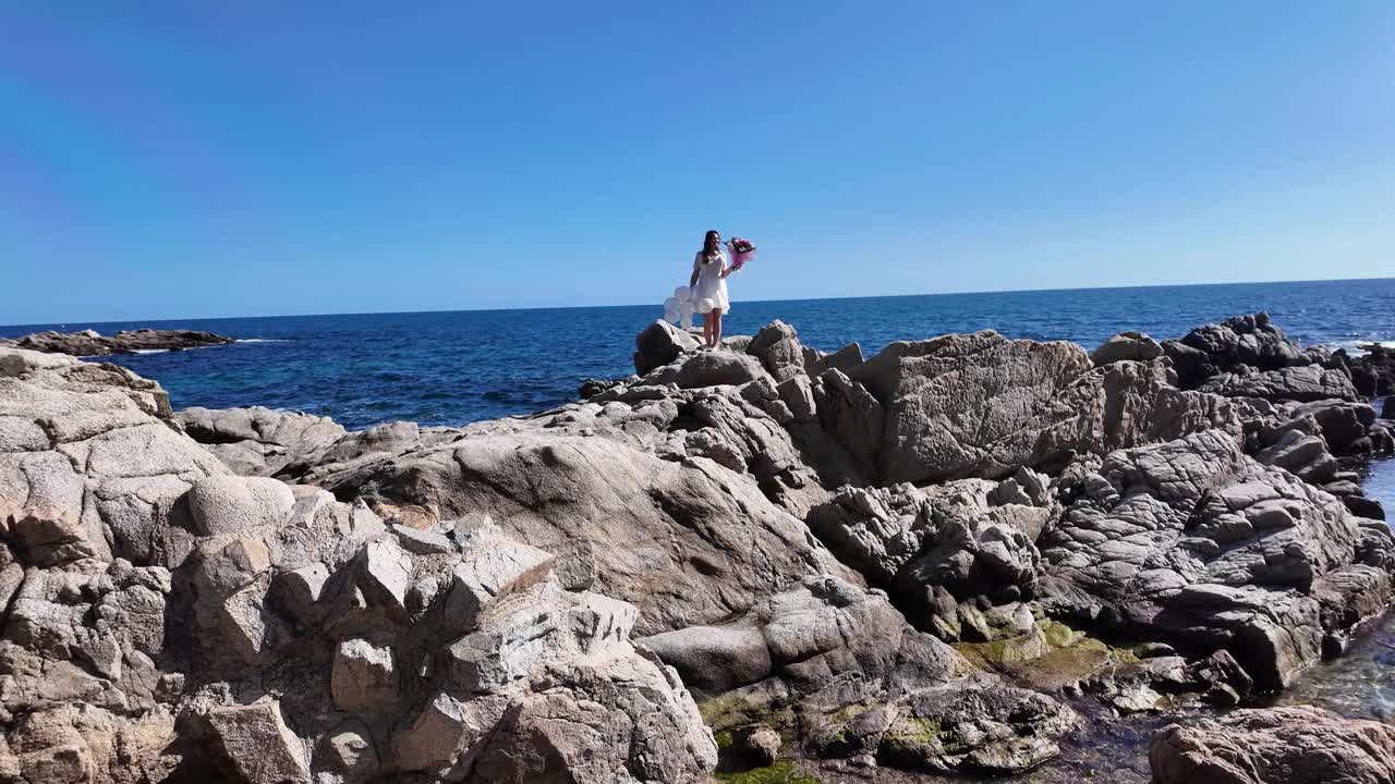 快乐的美丽女孩带着花束和白色气球，庆祝生日和女人节，大海和岩石，4K视频素材