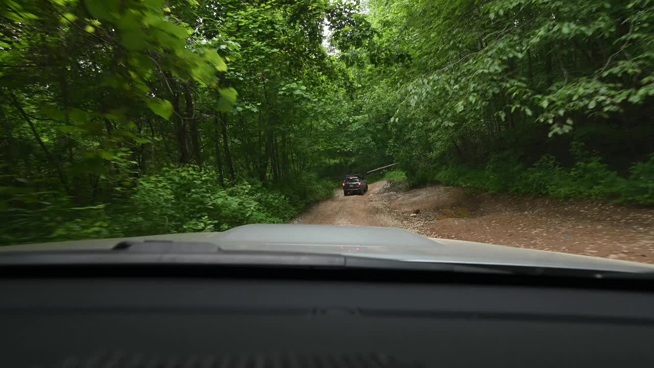 两辆陆路车辆驶过陡峭的森林道路，经过一棵倒下的树视频下载