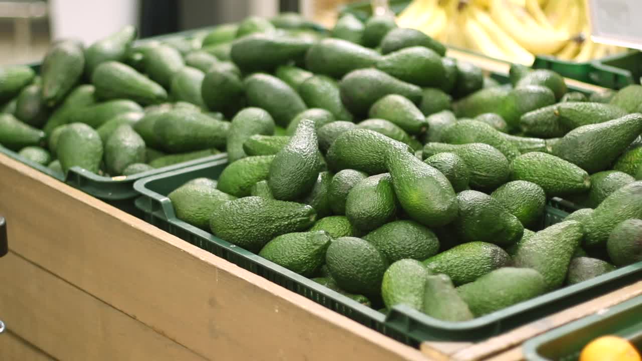 一名买家在超市挑选牛油果。男顾客在杂货店买青菜。健康饮食理念。视频素材