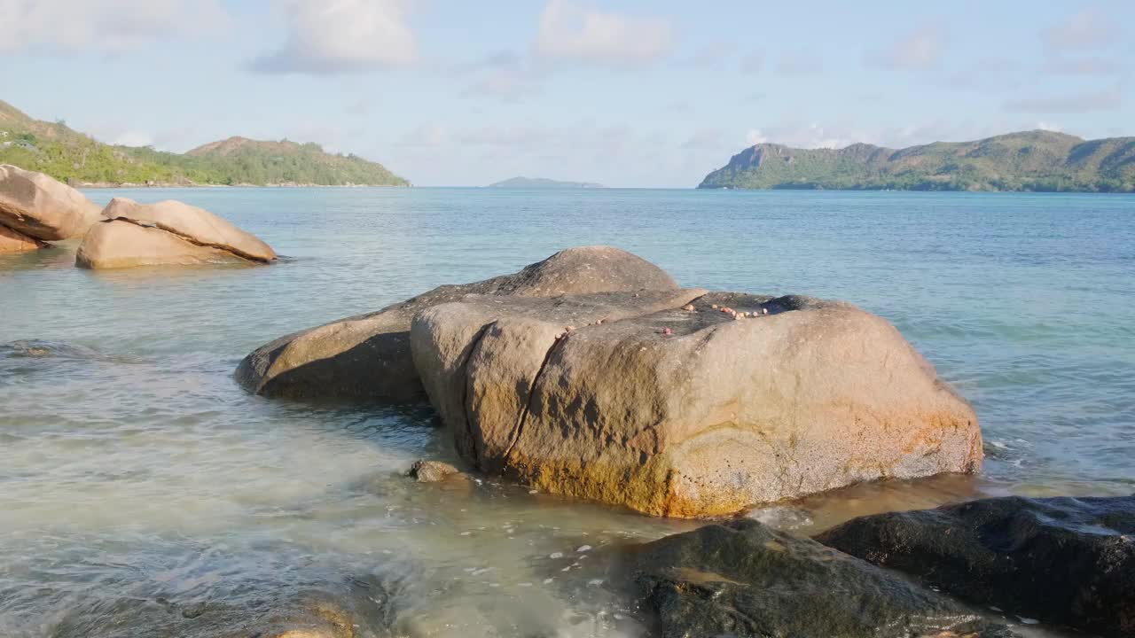 一块大石头坐落在海滩附近的海洋里。水面平静，天空晴朗视频下载