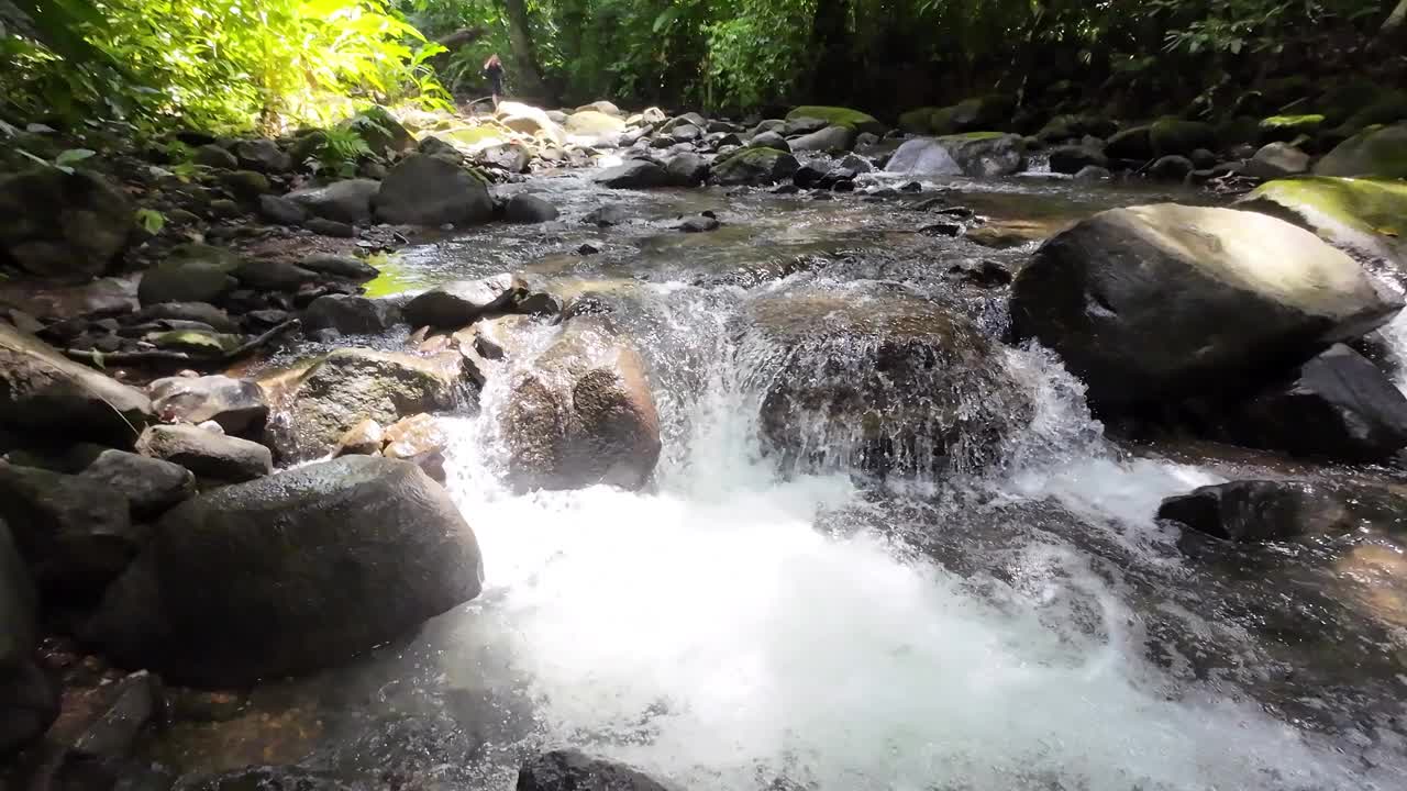 温和的跟踪拍摄通过一个风景如画的河流与雄伟的瀑布和大石头4K分辨率视频下载