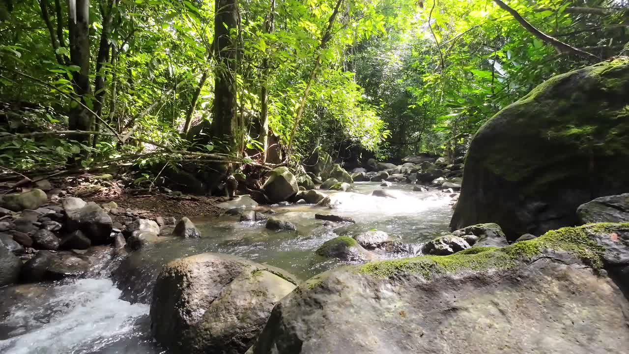 温和的跟踪拍摄通过一个风景如画的河流与雄伟的瀑布和大石头4K分辨率视频下载