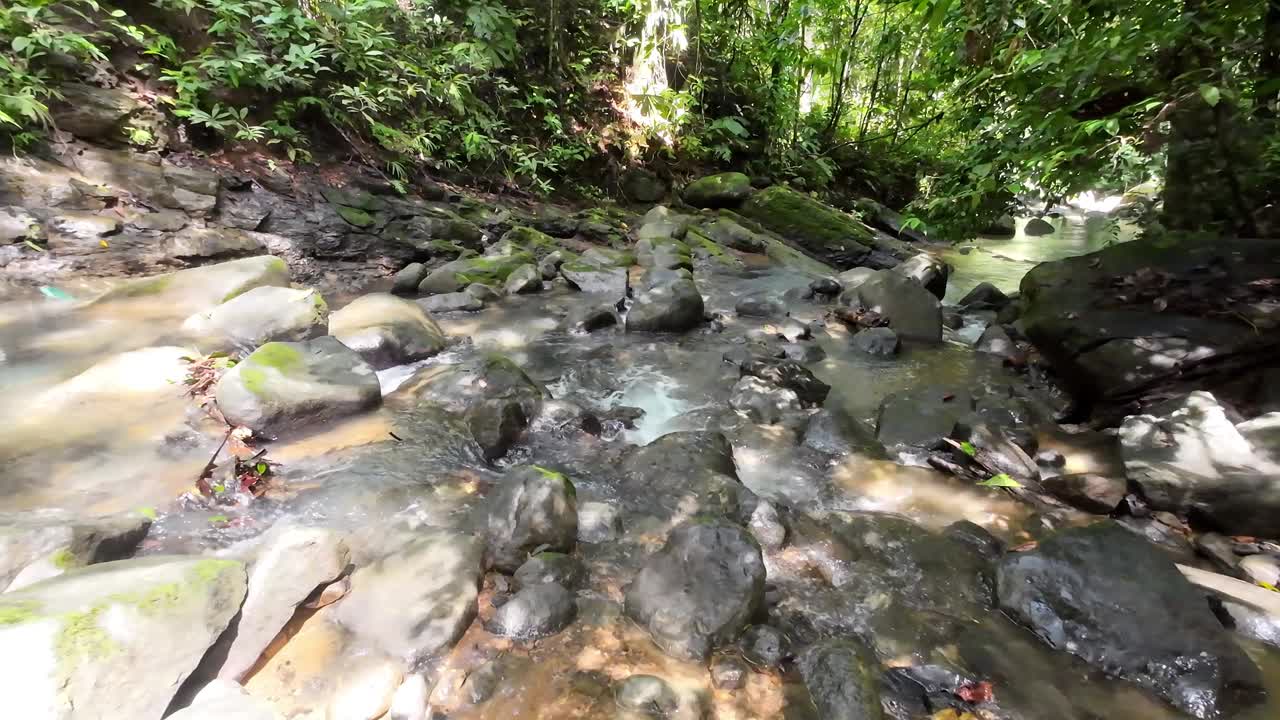 温和的跟踪拍摄通过一个风景如画的河流与雄伟的瀑布和大石头4K分辨率视频下载