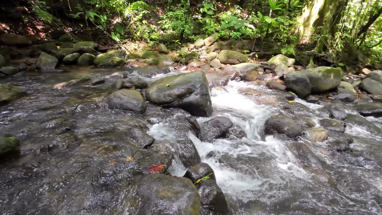 温和的跟踪拍摄通过一个风景如画的河流与雄伟的瀑布和大石头4K分辨率视频素材