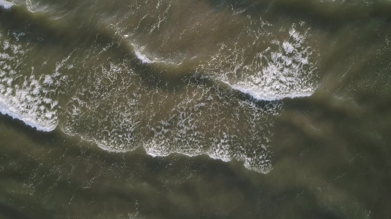 海浪冲击着海岸的一片水域。波浪是白色的，水是深色的。海浪轻轻拍打着海岸，景色平静祥和视频下载