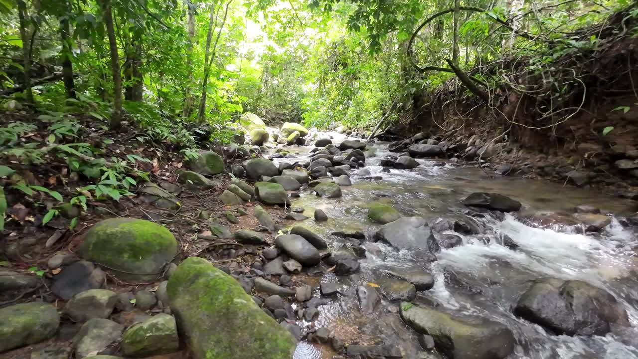 温和的跟踪拍摄通过一个风景如画的河流与雄伟的瀑布和大石头4K分辨率视频下载