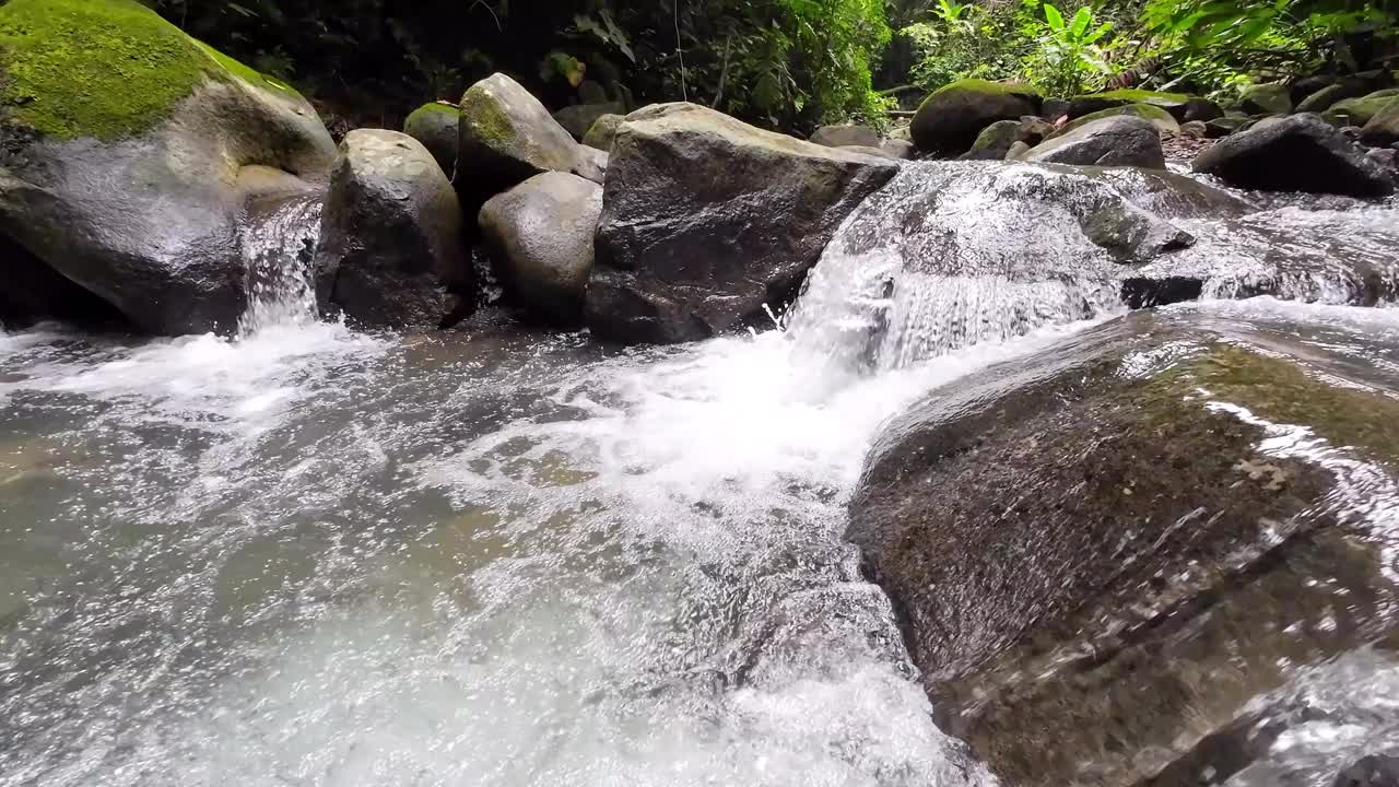 温和的跟踪拍摄通过一个风景如画的河流与雄伟的瀑布和大石头4K分辨率视频下载