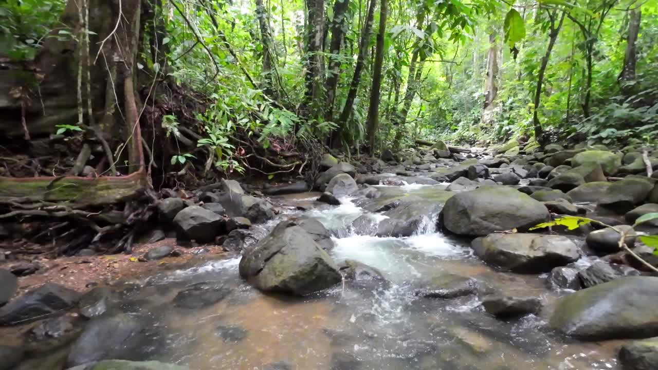 温和的跟踪拍摄通过一个风景如画的河流与雄伟的瀑布和大石头4K分辨率视频下载