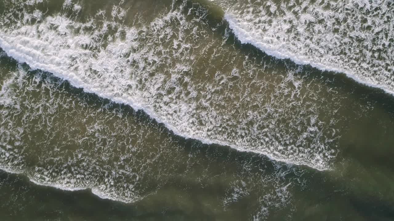 海浪冲击着海岸的一片水域。波浪是白色的，水是深色的。海浪轻轻拍打着海岸，景色平静祥和视频下载