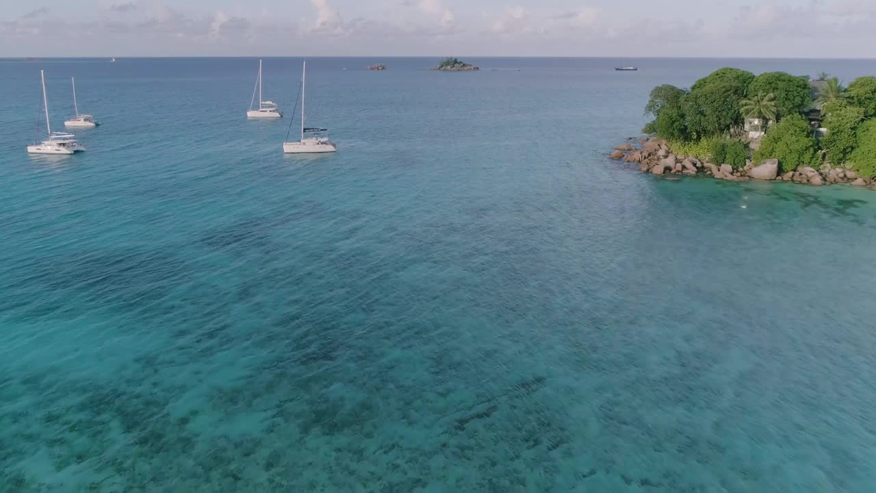 空中美丽的蓝色海洋上漂浮着几艘船。这些船很小，分散在水面上。这里的景色宁静祥和，船只增添了一种休闲的感觉视频下载