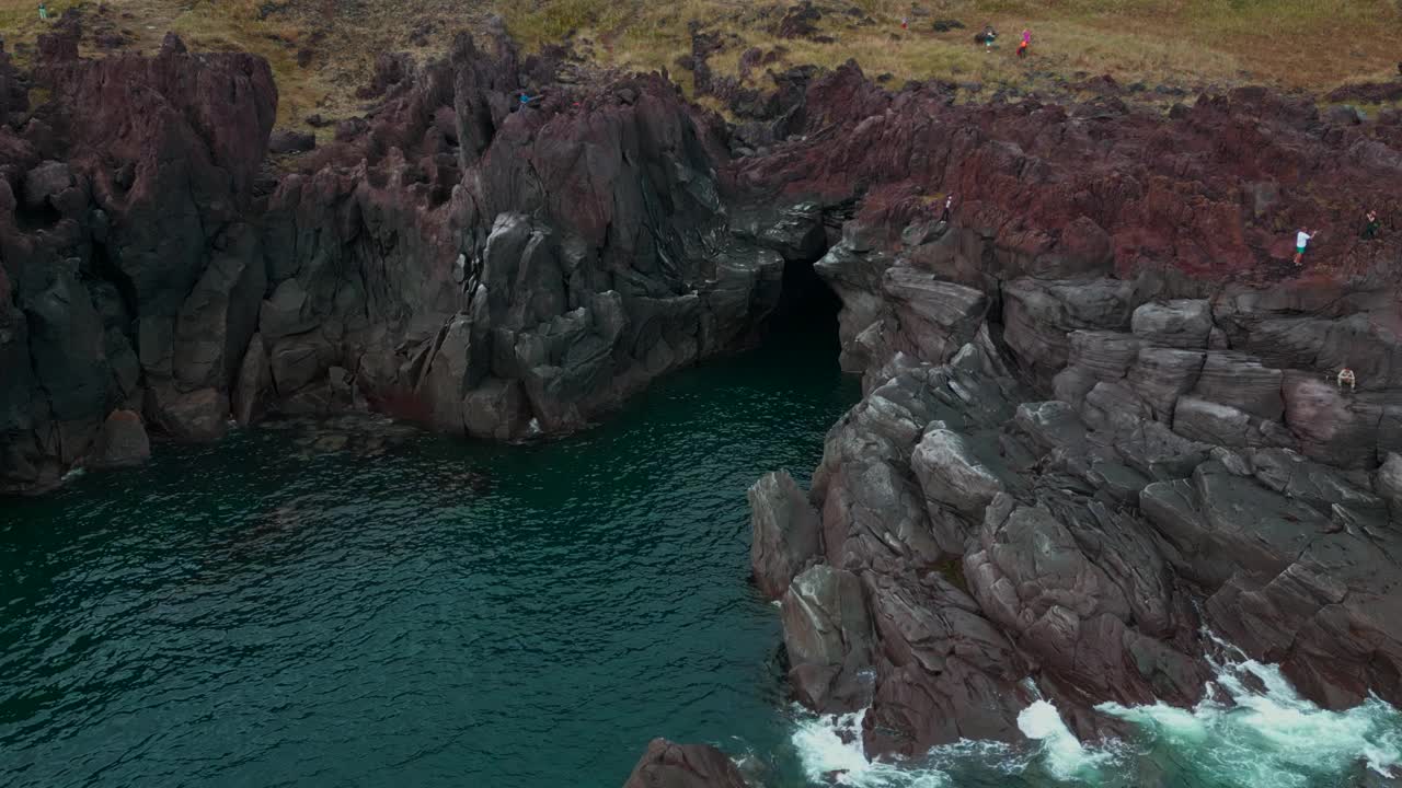 岛上悬崖和碧海的壮丽景色。夹。飞近那个不知名的小黑暗洞穴。视频素材