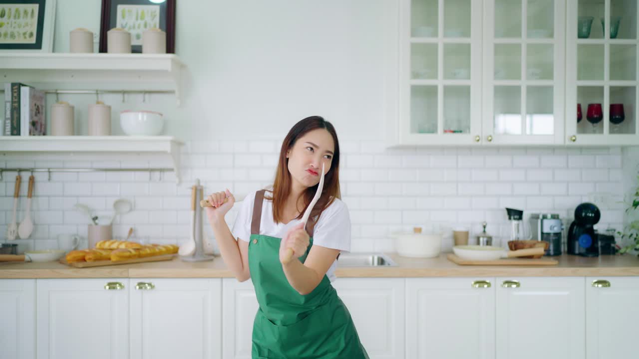 年轻的亚洲女人在厨房里跳舞。一个美丽的女人在周末的空闲时间在家里放松的快乐视频素材