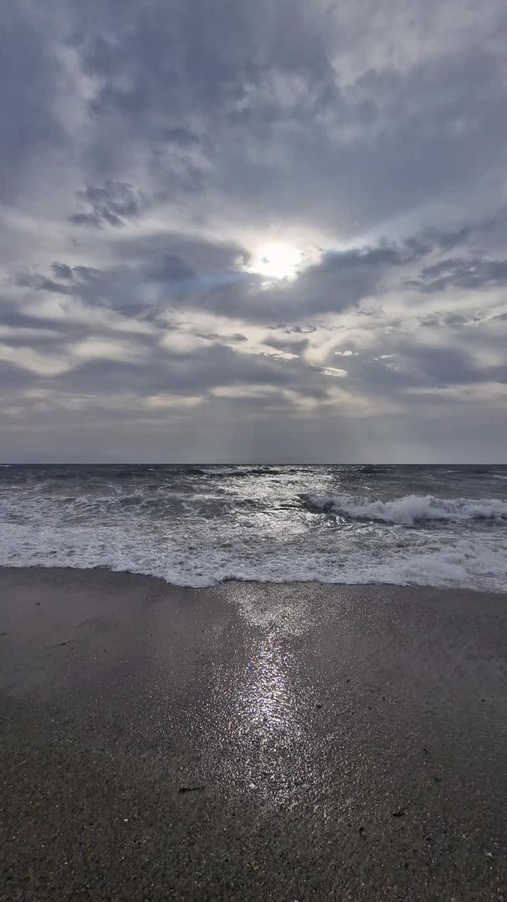 海面上的小波浪，映衬着金色的日出，动作缓慢。一大片冉冉升起的太阳从海面上升起，在水面上形成了一条阳光明媚的小路。视频下载