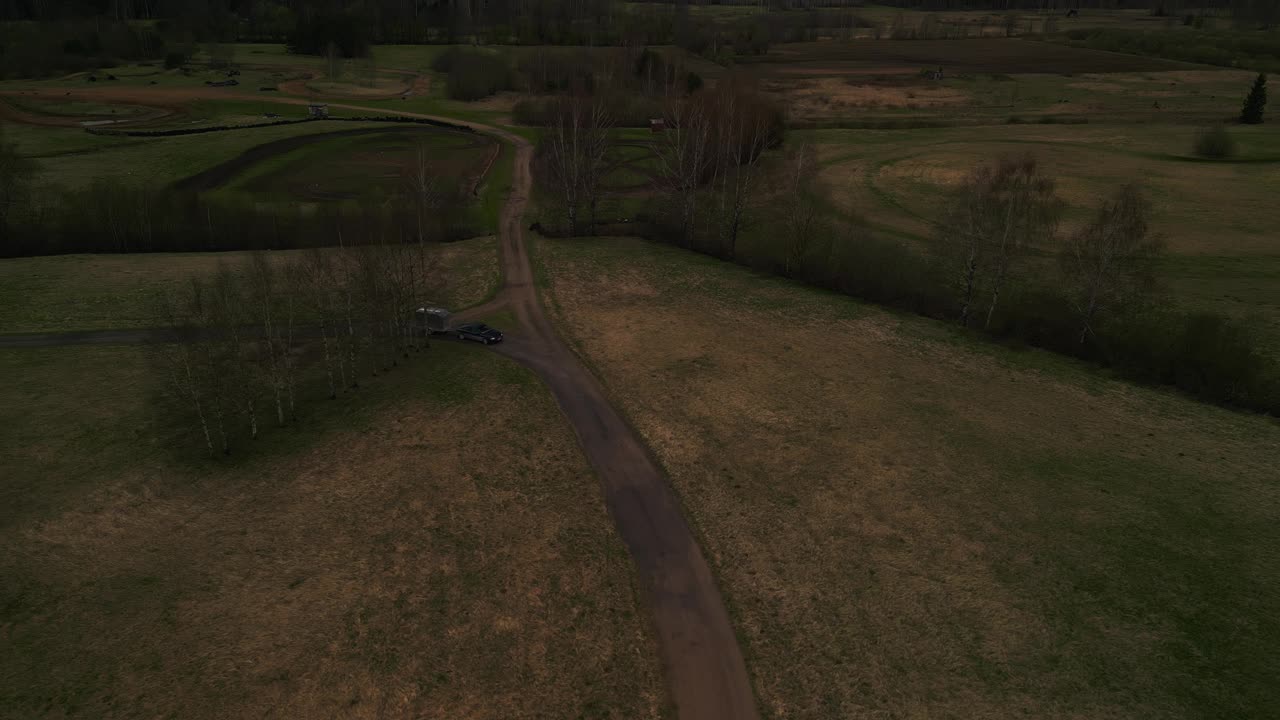 鸟瞰图的汽车在泥泞的道路上通过草地景观视频素材