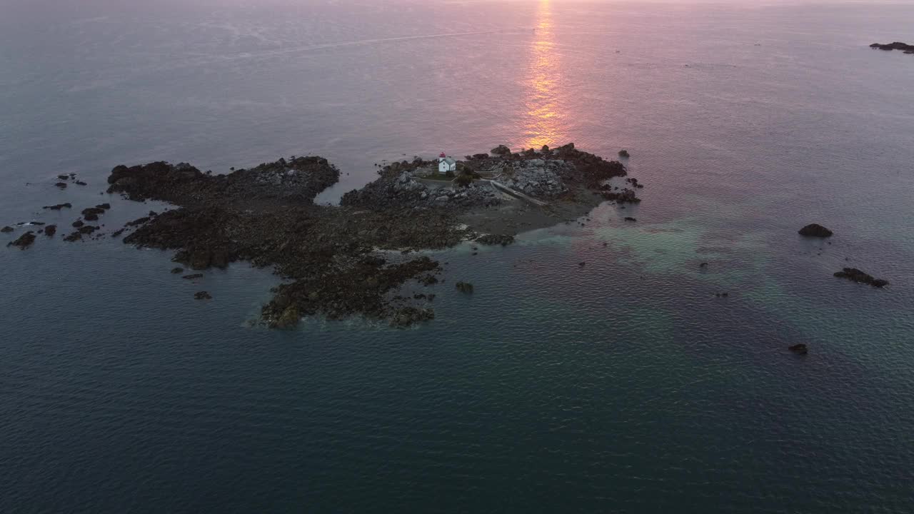 在法国布列塔尼海岸的清晨日出中，在海上乘船接近一个小岛。这个岛在圣魁波特里厄海岸上。视频素材