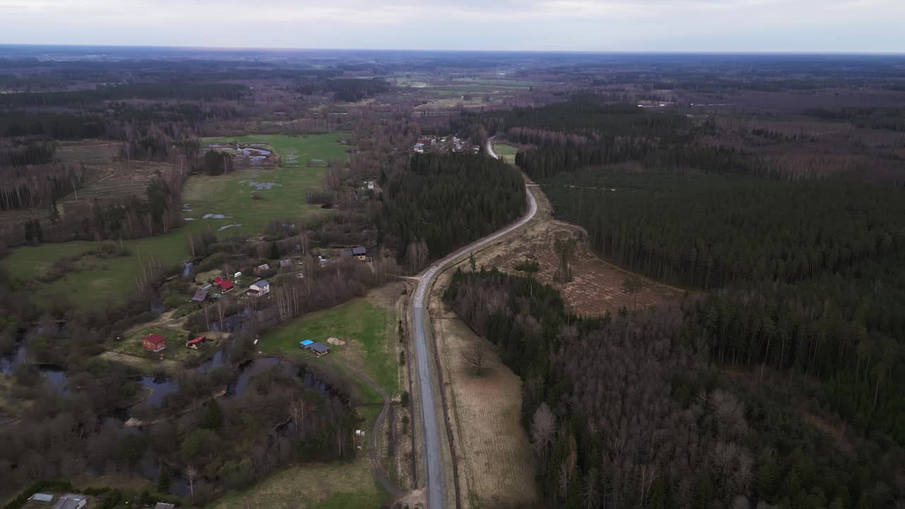 鸟瞰穿过森林、草地、山丘和天空的道路视频素材