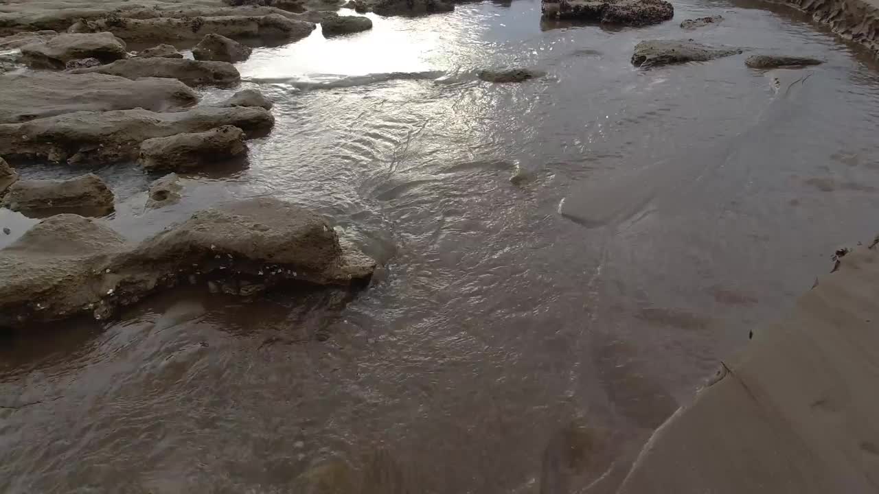 在自然环境中，清澈的水流过岩石和沙子的宁静场景。4K镜头视频下载